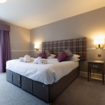 Cosy hotel room with king-sized bed, warm lighting, and a view through French doors.