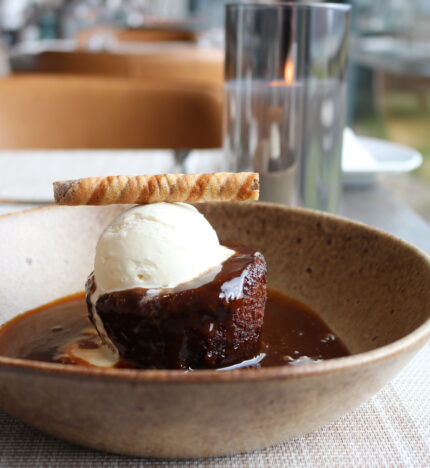 Warm dessert with ice cream served in a cosy restaurant setting overlooking green gardens.