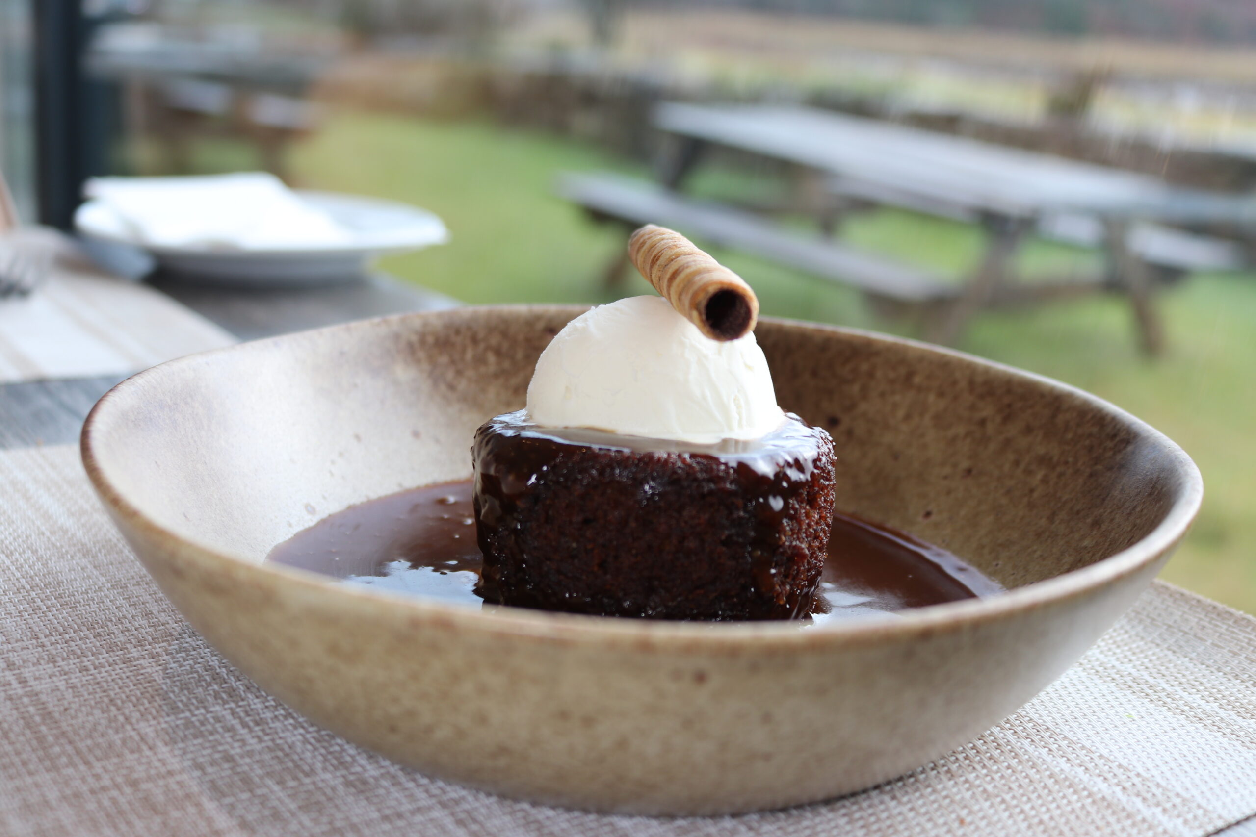 Sticky toffee pudding with cream and a wafer, served in a cosy dining area at Balmacara.