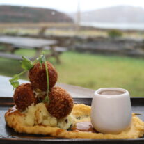 A delicious gourmet dish with scenic outdoor views at a Balmacara hotel restaurant.