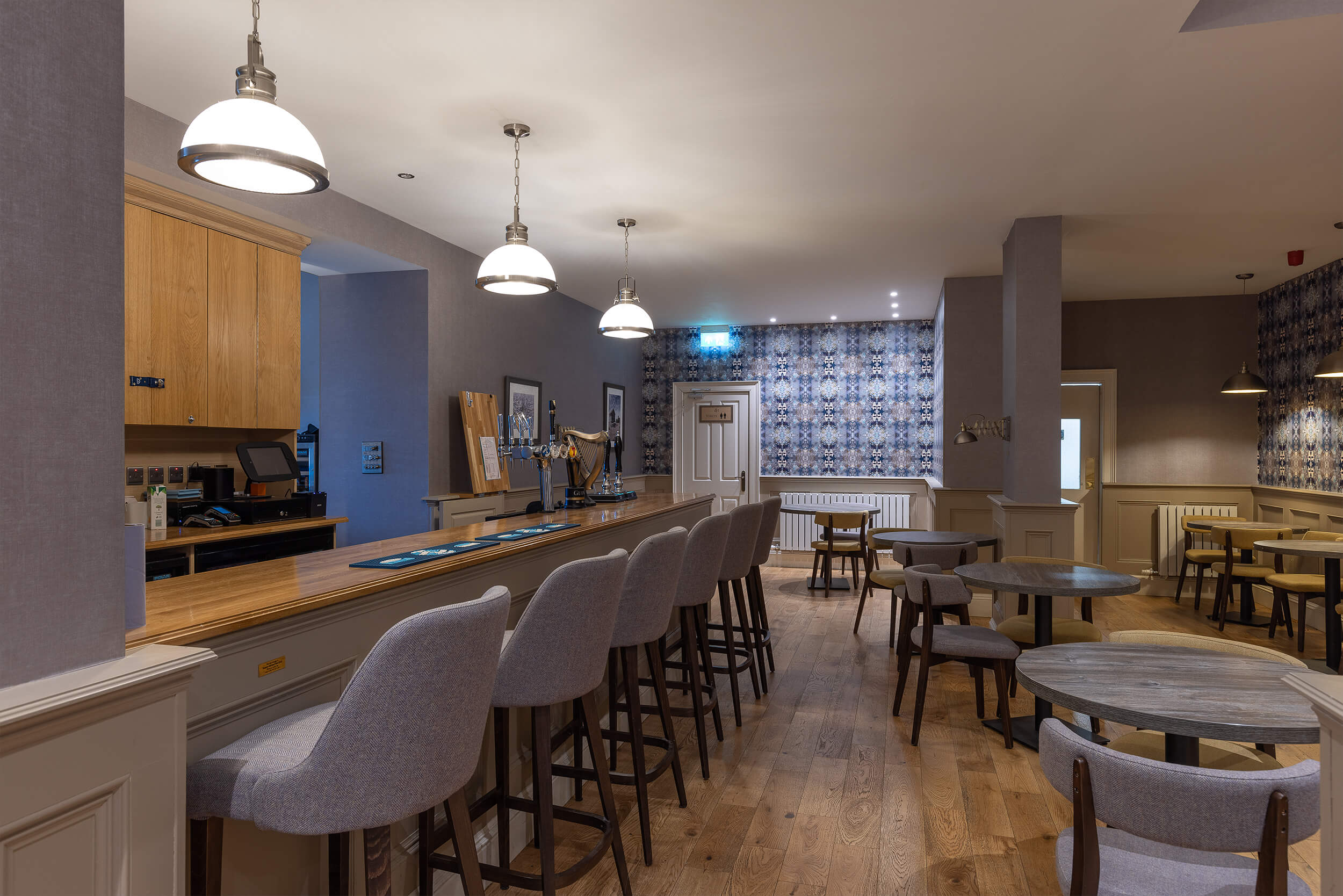 Cosy hotel bar with warm lighting, wooden floors, and seating area for family gatherings.