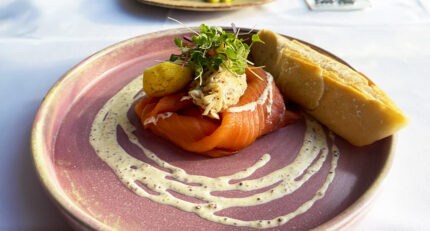 Gourmet smoked salmon dish with bread roll on a pink plate at Balmacara hotel restaurant.