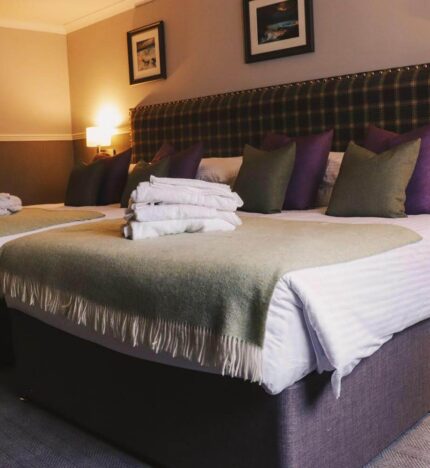Cosy hotel room with two inviting double beds, soft lighting, and warm decor.