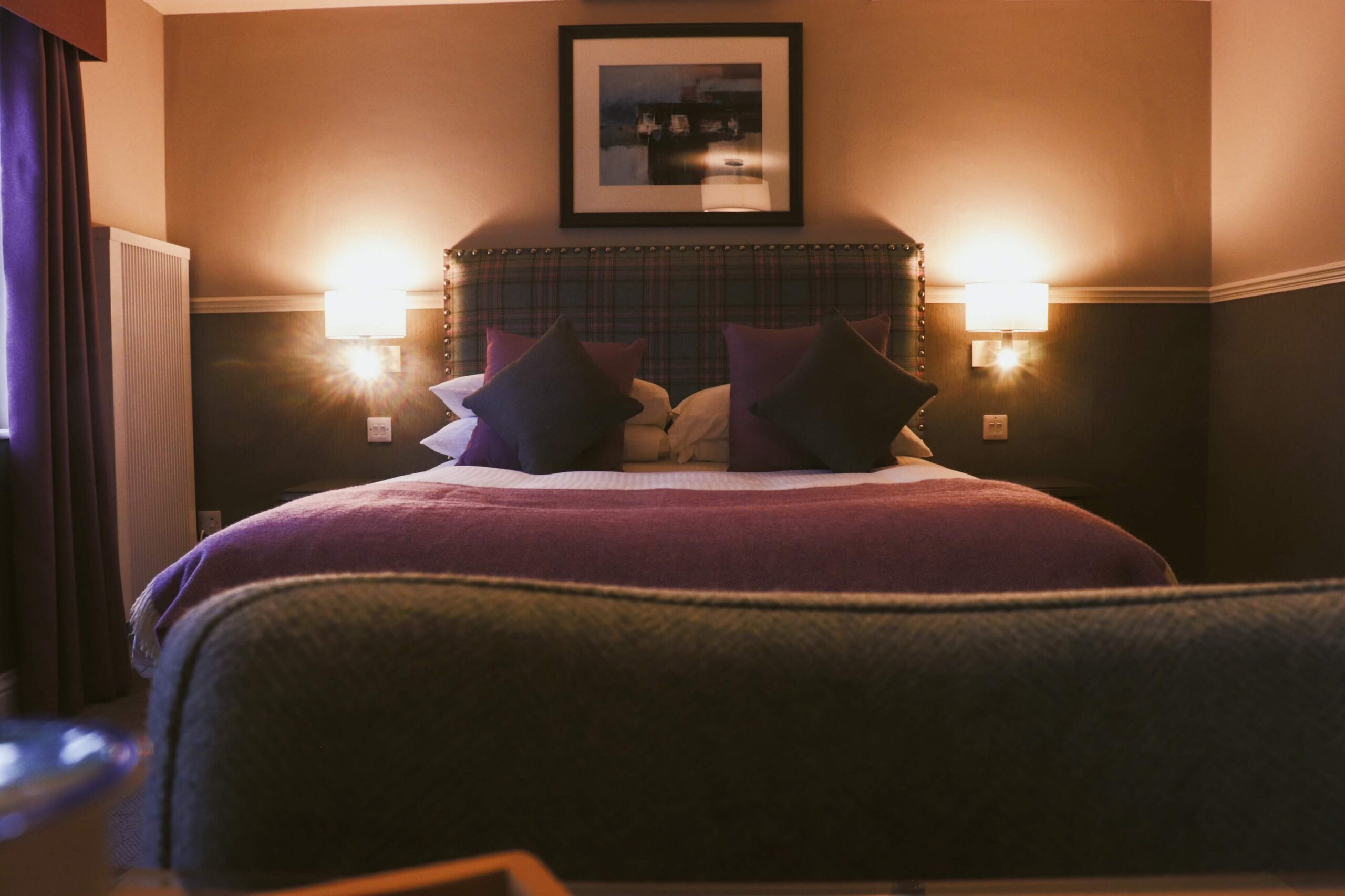 Cosy hotel room with soft lighting, plush bed, and warm decor for a relaxing stay.