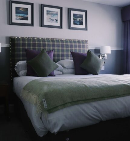 Cosy hotel room with a tartan headboard, plush pillows, and soft lighting, inviting and serene.