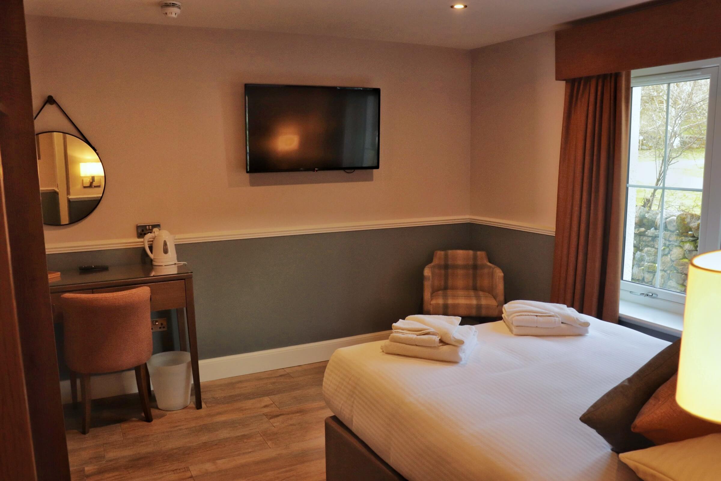 Cosy hotel room with a large bed, soft lighting, and scenic window view for a relaxing stay.