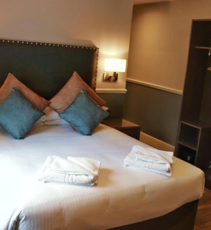 Cosy hotel room with plush pillows and neatly folded towels, inviting relaxation.