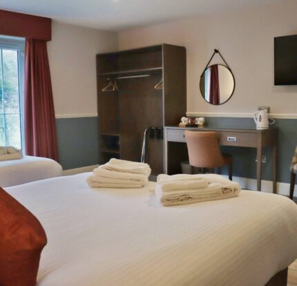 Bright, cosy hotel room with twin beds, desk, and scenic window view.