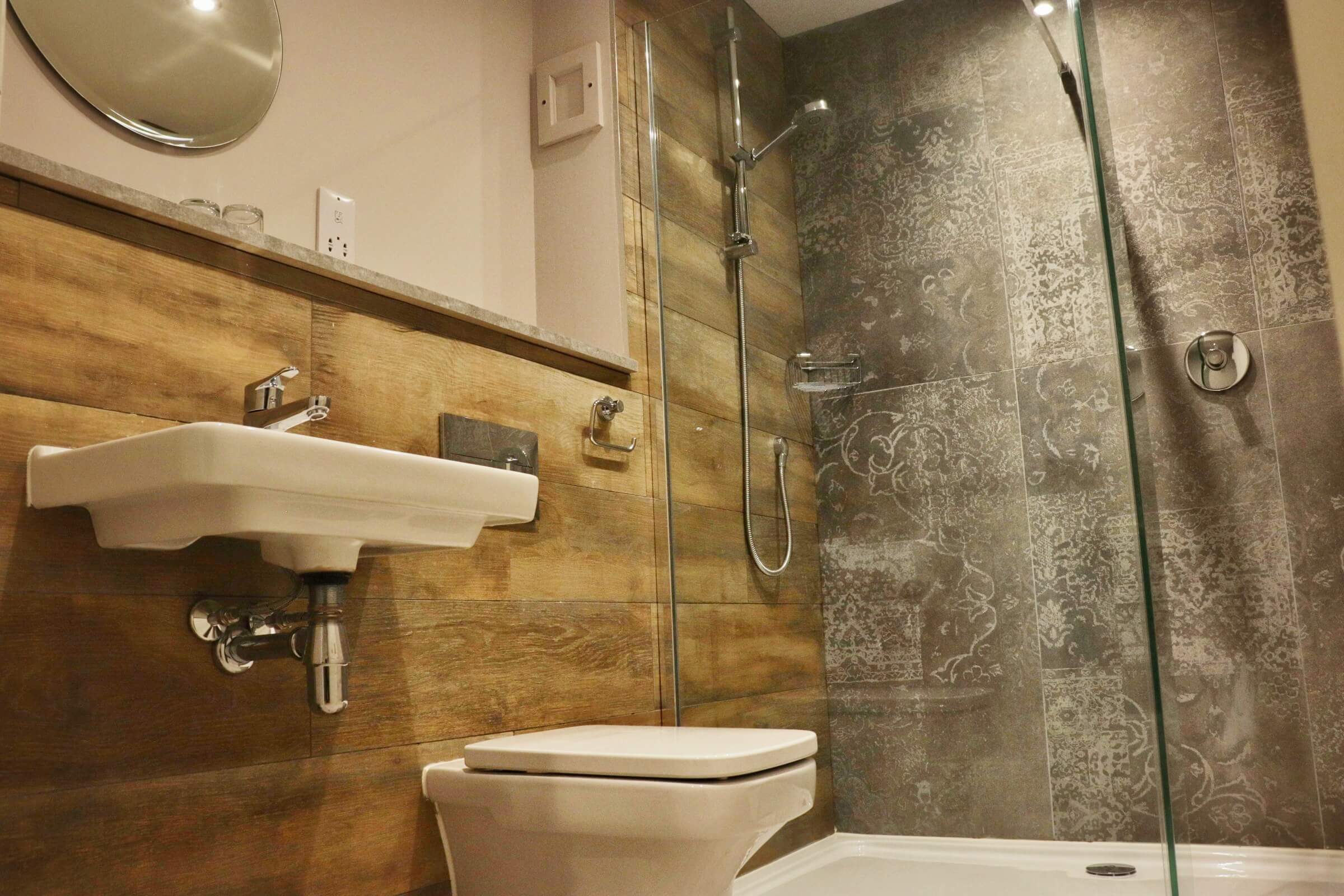 Modern bathroom with patterned tiles, sleek basin, and glass shower at Balmacara hotel.