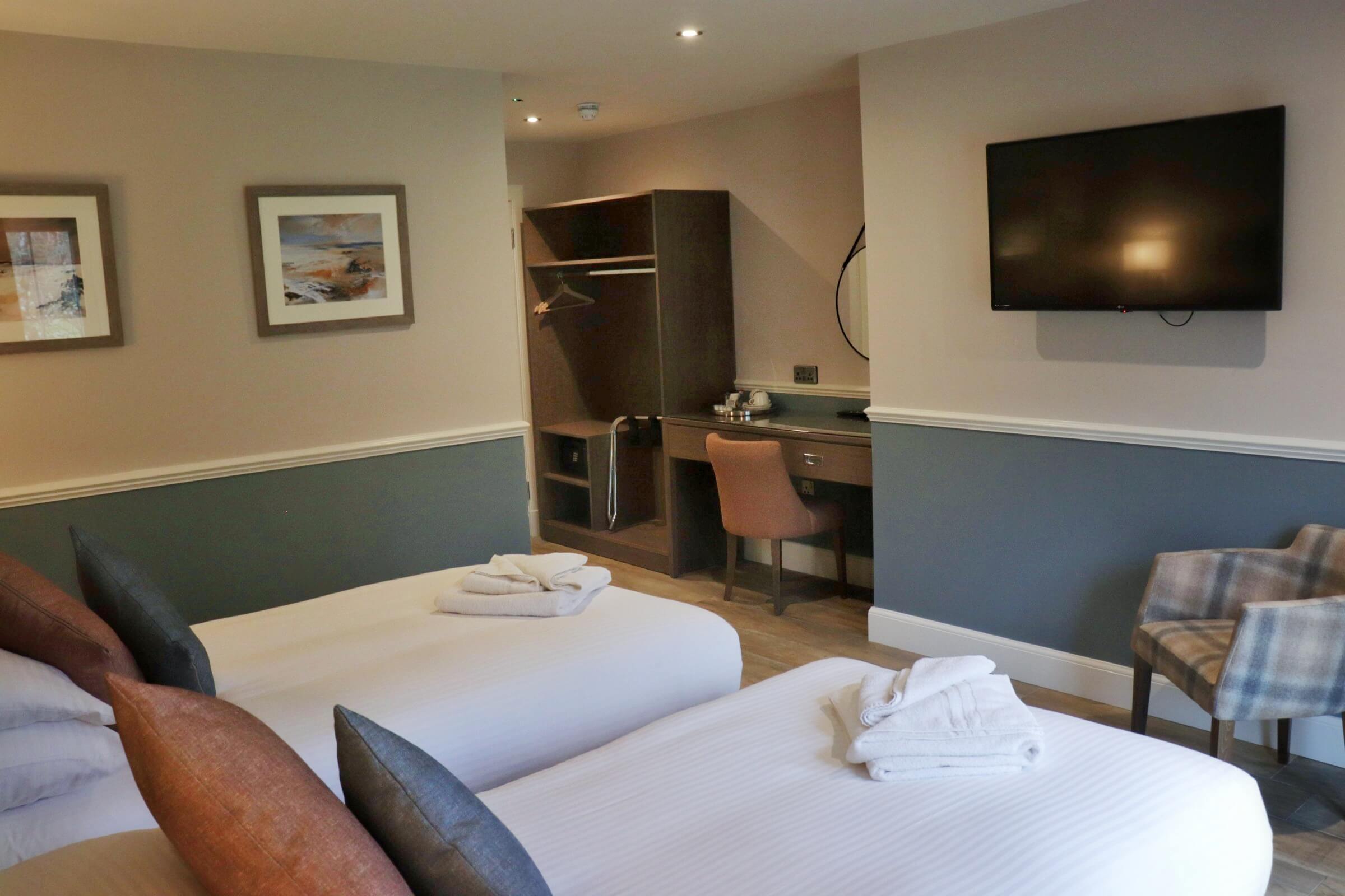 Cosy hotel room with two beds, a TV, and a desk, perfect for families or couples.