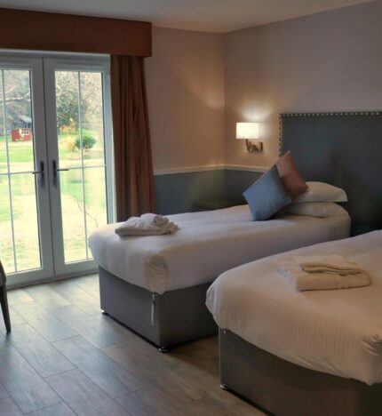 Cosy twin room in Balmacara hotel with garden view through large French doors.