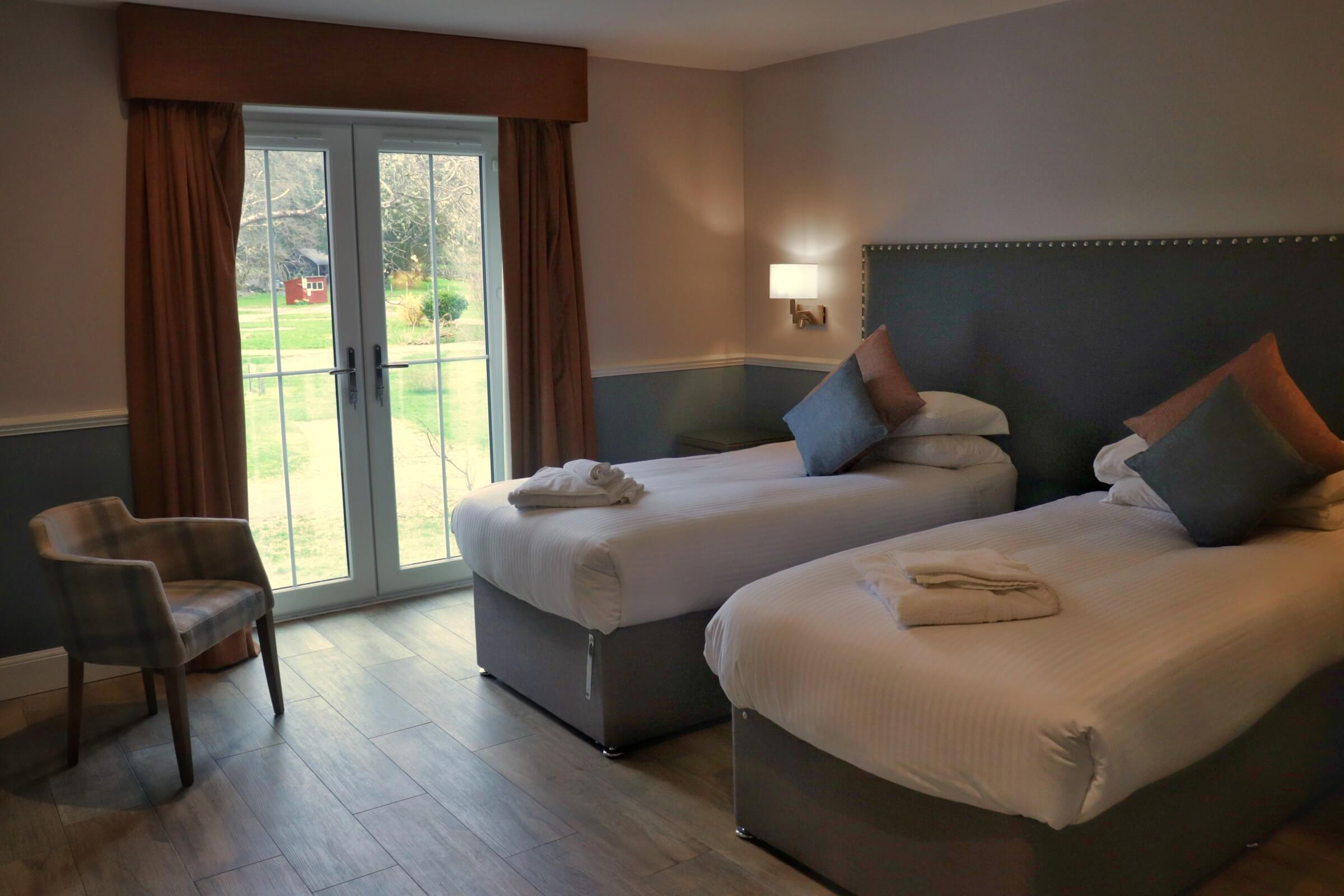 Cosy twin room in Balmacara hotel with garden view through large French doors.