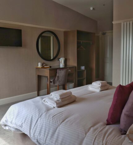 Cosy hotel room with a plush bed, soft pillows, a TV, and a welcoming tea station.