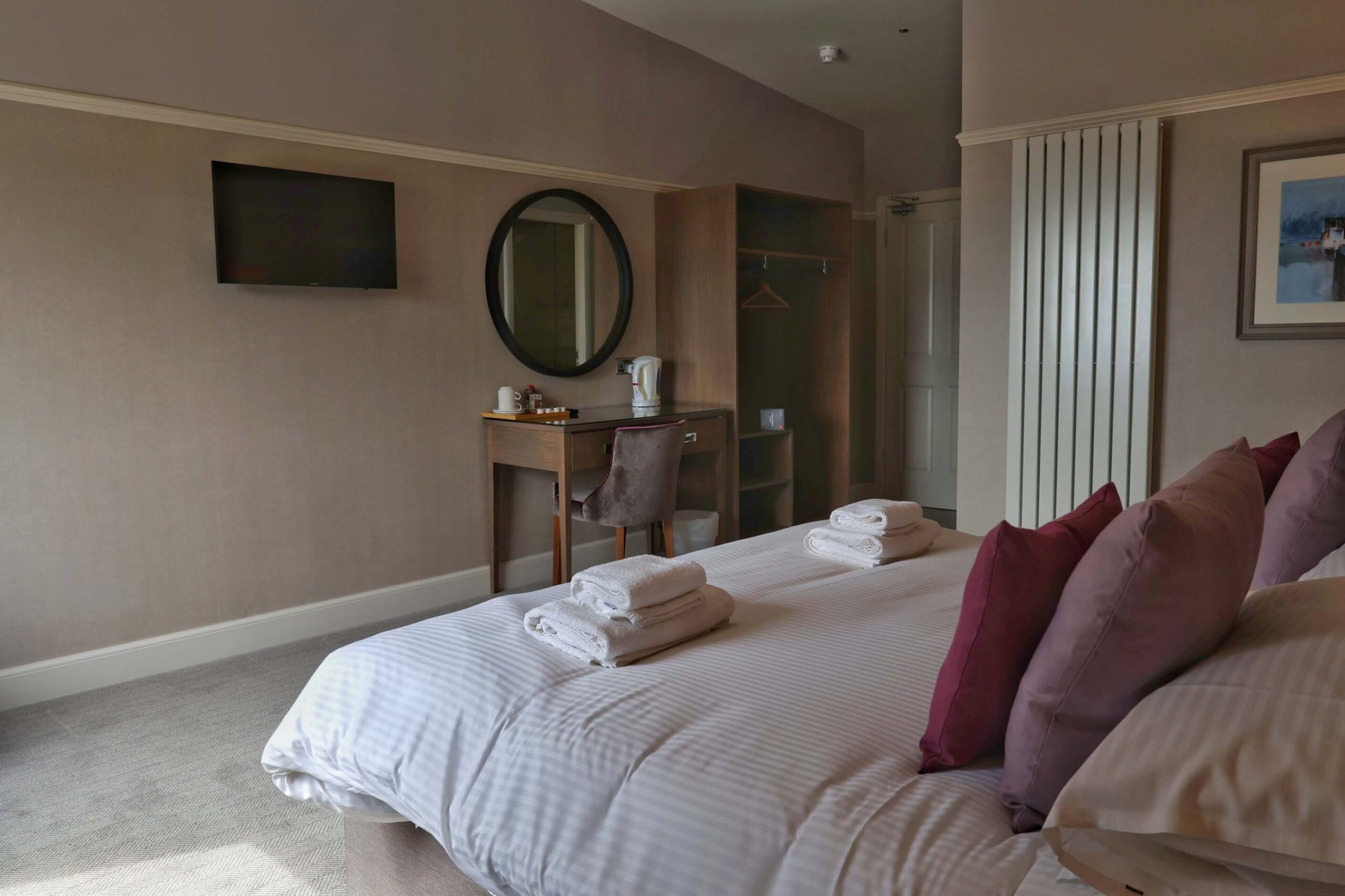 Cosy hotel room with a plush bed, soft pillows, a TV, and a welcoming tea station.