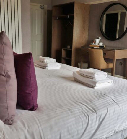 Elegant hotel room with plush pillows, fresh towels, and a cosy atmosphere for relaxation.