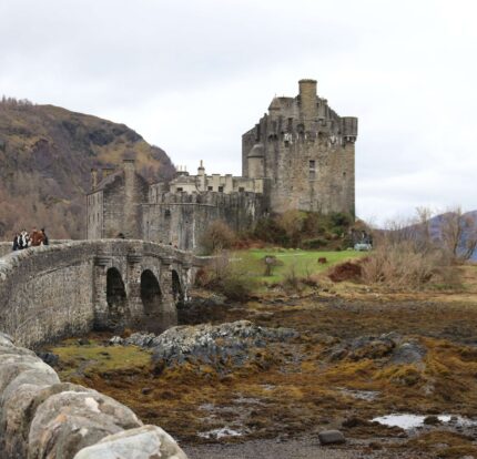Family enjoying a scenic walk towards historic Eilean Donan Castle in the Highlands.