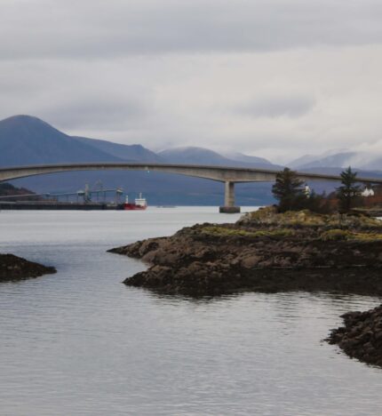 Scenic view of a bridge over calm waters with mountains in the background near Balmacara.