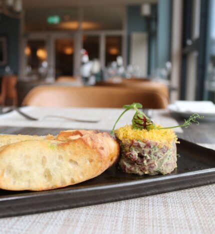 Elegant hotel dining with savoury dish and bread by a sunlit window.