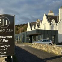 Balmacara Hotel exterior with a welcoming sign for the restaurant and bar, set against a scenic backdrop.