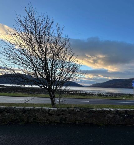 Scenic view from Balmacara hotel, overlooking mountains and a tranquil loch at sunset.