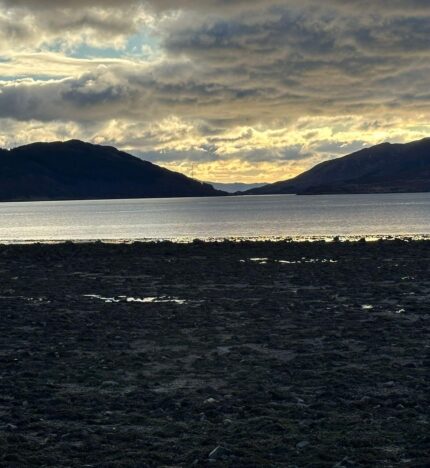 Serene coastal view from Balmacara, with soft evening light over water and rolling hills.